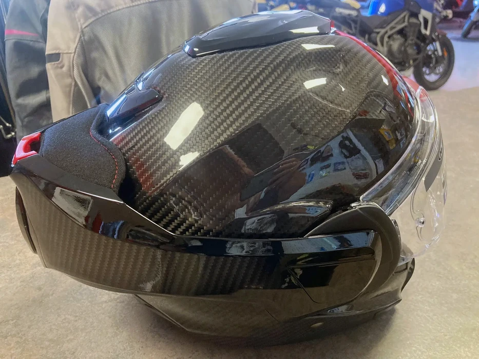 Intérieur d'un magasin ou atelier, personne en vêtement beige examine un casque de moto