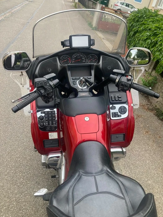 Extérieur urbain, moto touring rouge stationnée sur route pavée près de végétation