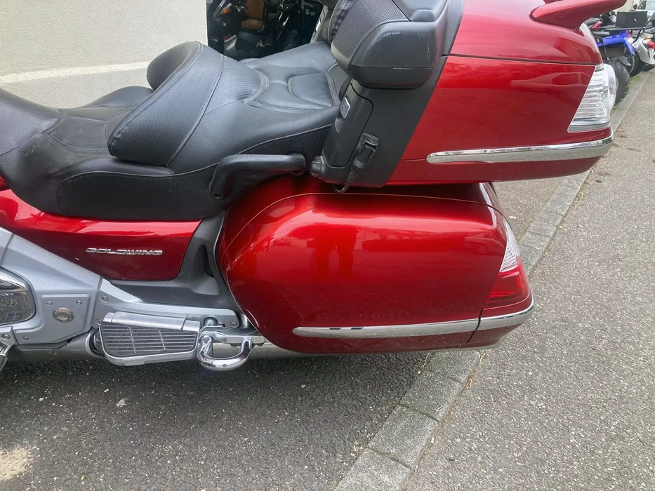 Scène extérieure sur parking, moto touring Honda Gold Wing rouge et grise stationnée