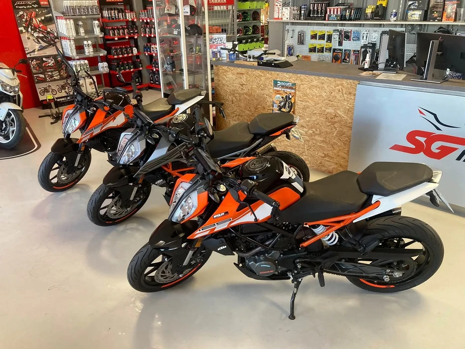 Moto sport-touring Yamaha Tracer garée sur route goudronnée, équipée d'un top-case arrière et pare-brise, stationnée devant végétation sèche et bâtiments résidentiels