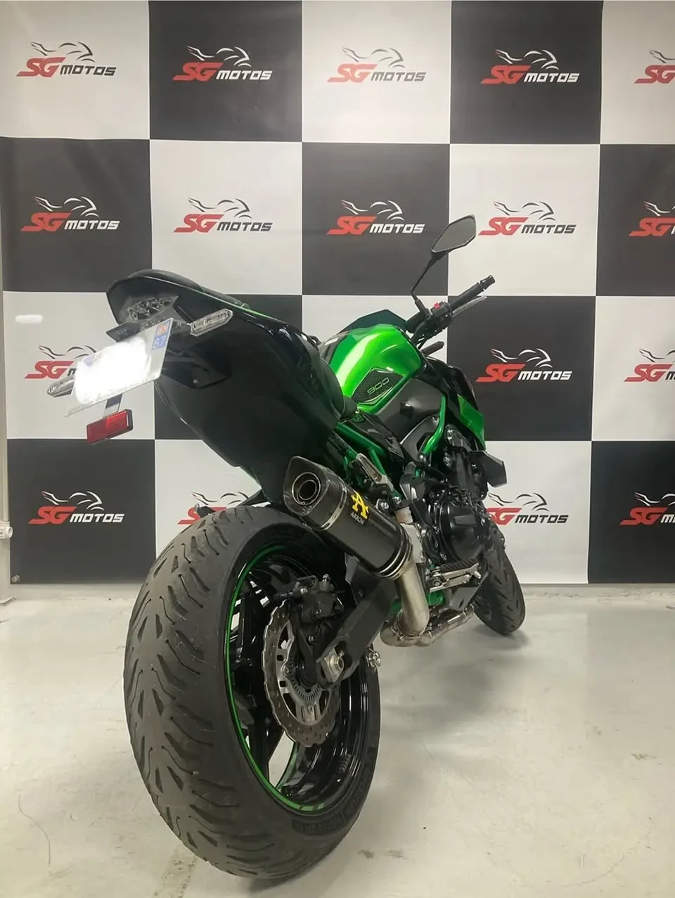 Scène extérieure avec moto de tourisme rouge Honda Gold Wing stationnée devant haie végétale