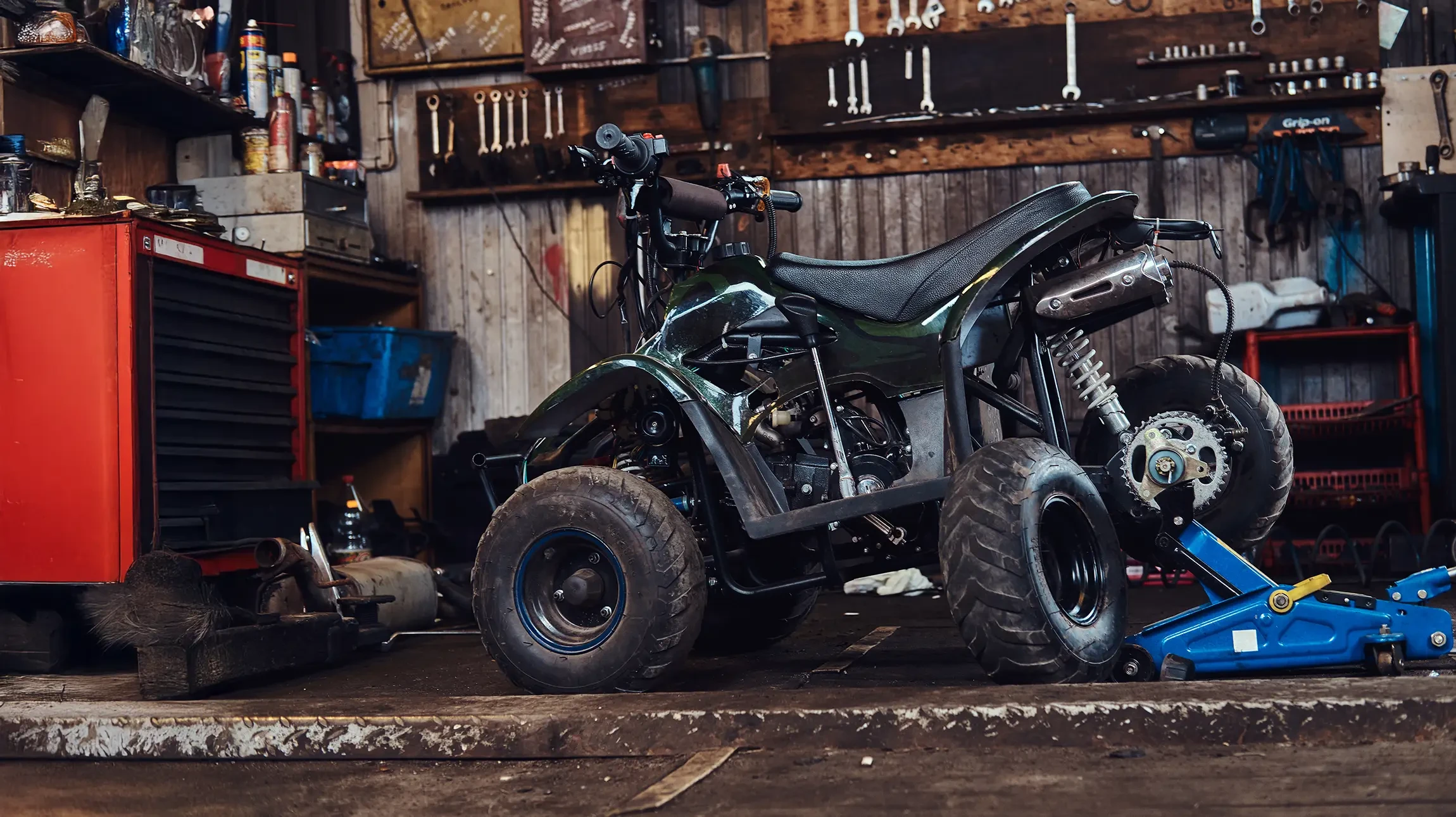 Atelier de r&eacute;paration v&eacute;lo en int&eacute;rieur, m&eacute;canicien ajustant le d&eacute;railleur arri&egrave;re d'un v&eacute;lo bleu
