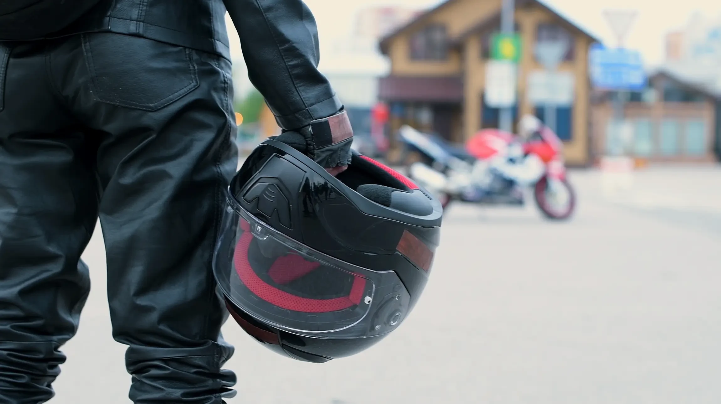Une personne en jean et t-shirt blanc pr&eacute;pare des sacoches de moto noires avec sangles en cuir sur une moto vintage dans un garage ou atelier