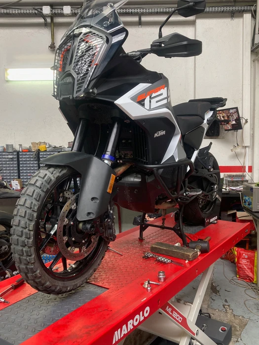 Intérieur d'un atelier de réparation de motos et scooters avec un scooter blanc en premier plan