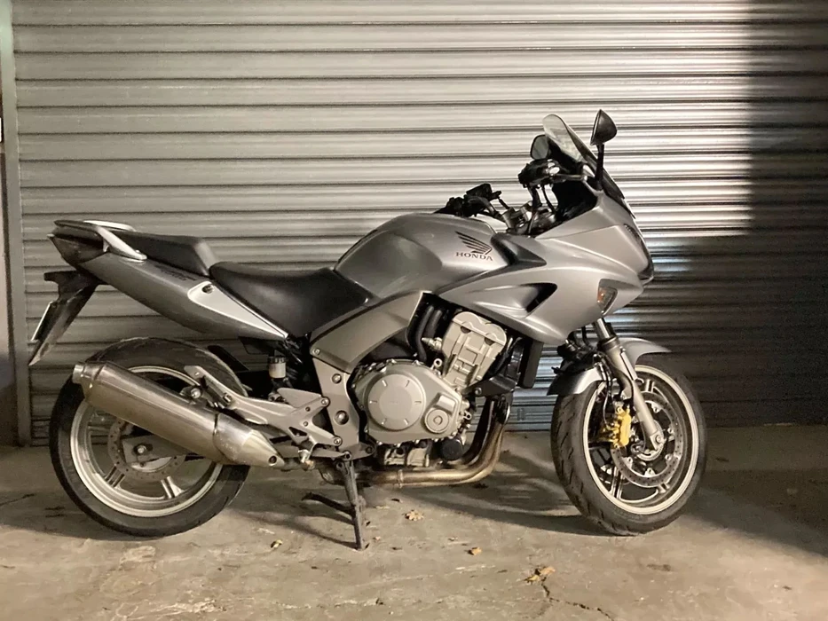 Atelier de réparation moto avec mécanicien travaillant sur une moto adventure touring noire et grise