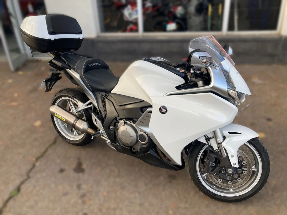 Atelier de réparation moto avec mécanicien travaillant sur une moto sportive surélevée sur pont élévateur rouge Marolo